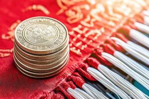 Golden i-ching coins symbolizing wealth and prosperity stacked on red silk with traditional Chinese patterns photo