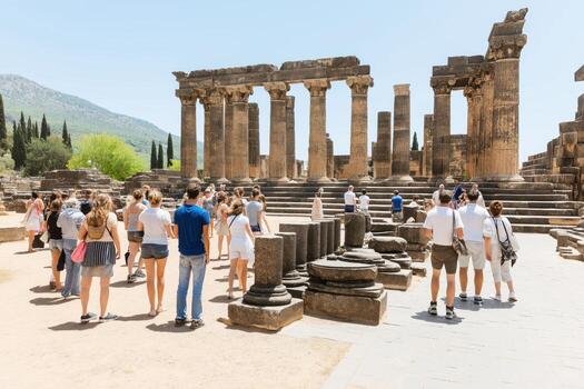 Visitors exploring ancient ruins of Delphi under a clear sky surrounded by fading colors of history photo
