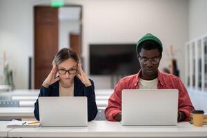 Concentrated serious students learning sitting in desktop in college lecture classroom with laptops. photo