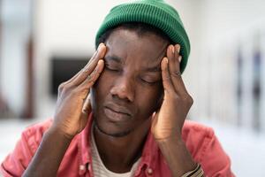 Unhappy black man touch forehead feel headache from long hours computer overwork overtime deadline. photo