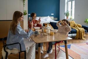 Loving mom takes pictures on smartphone as son fooling around with bread toast at family breakfast photo