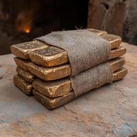 Stack of gold bars wrapped in burlap on a rustic surface photo
