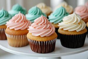 Close up of pastel cupcakes with swirled frosting on a white cake stand photo