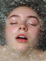 Woman with freckles submerged in water, eyes closed photo