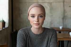 Young woman with freckles and light eyes wearing a beanie and sweater photo