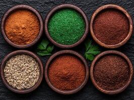 Assortment of various spices in wooden bowls on dark background photo