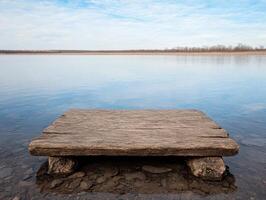 Rustic wooden platform on tranquil lake under blue sky photo