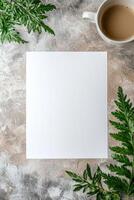 Blank paper mockup surrounded by green leaves and a cup of coffee on a textured background photo