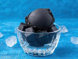 Black ice cream in a glass bowl with ice cubes photo