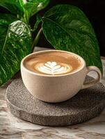 Close up of a latte with latte art in a beige cup on a gray stone coaster photo