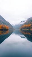 Misty Morning Lake with Autumn Forest Reflections and Mountain View Capturing Tranquil Beauty in Nature Landscape photo