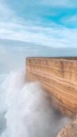Majestic Ocean Waves Crashing Against Rugged Cliffs Under Clear Blue Sky Evoking Serenity and Natural Wonder with Dramatic Water Splash Seascape Perfect for Modern Coastal Decor photo