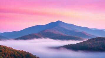 Scenic view of layered mountains covered with autumn foliage and low-lying fog under a vibrant pink and orange sunrise sky Tranquil nature and landscape concept for travel and seasonal design photo