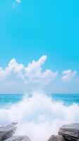 Ocean Waves Crashing Against Stones Under Clear Blue Sky with Fluffy Clouds photo