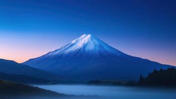 Stunning Snow-Capped Mountain at Twilight Under Starry Night Sky Featuring Majestic Landscape With Deep Blue Atmospheric Vibes and Peaceful Misty Foreground Perfect for Nature Enthusiasts photo