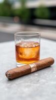 Whiskey Tumbler with Ice and Cuban Cigar on Outdoor Table Surface, Highlighting Luxurious Leisure in Natural Light Photography and Premium Lifestyle Theme photo