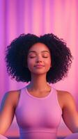 Serene Young Woman with Curly Hair Meditating in Pink Yoga Attire Against Soft Pastel Background for Mindfulness and Relaxation Concept photo