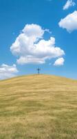 Concept of Redemption with Cross on Hill Against Vibrant Blue Sky and Fluffy Clouds photo
