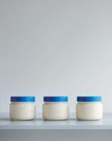 three jars of cream sitting on a table with a blue lidthree jars of cream sitting on a table with a blue lid. photo