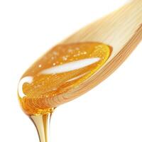 Honey drips from a wooden spoon, highlighting its golden texture and viscosity in a close-up view photo