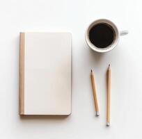 Blank notebook and coffee cup on a minimalist table with pencils ready for writing or sketching photo