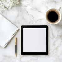Workspace with tablet, notebook, pen, and coffee on marble surface creating a calm work environment for productivity photo