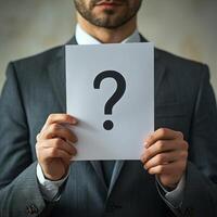 Businessman holding a blank paper with a question mark in a corporate setting photo