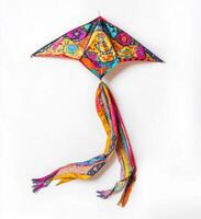 Colorful patterned kite hangs against a white background in a playful arrangement with its vibrant tail flowing photo