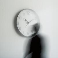 Person walking past a blurred clock highlighting the passage of time in a minimalist setting photo
