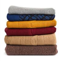 Warm and cozy stack of knitted sweaters displayed in an organized manner at a home setting during autumn photo