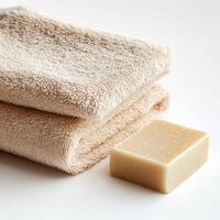 Clean towels and a bar of soap arranged neatly on a light surface for a relaxing bath experience photo
