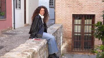 A Young Woman is Enjoying a Relaxing Moment while Sitting on a Stone Wall in a Scenic Setting video