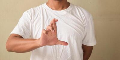 Young man showing crossed finger gesture in sign language photo