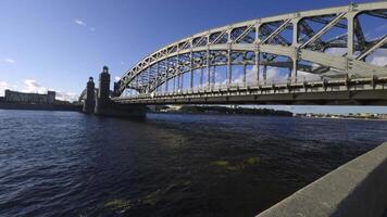 A stunning wide-angle view of the Bolshoy Obukhovsky Bridge in Saint Petersburg under a clear blue sky, showcasing its majestic arches, towering structures, and the serene surrounding water video