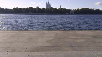 A tranquil view of the iconic Smolny Cathedral from across the river in Saint Petersburg, with its blue and white domes rising above the trees and reflecting beautifully in the calm river waters video