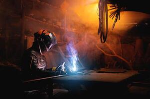 Welder using tool and sparks are generated, welding process in garage, hands with tool in protective clothing and helmet, hobby for adults photo