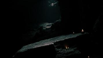 Mysterious cave illuminated by flickering candlelight in serene darkness video