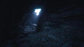 Exploring a dark cave with a bright opening and rocky terrain video