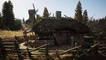 Rustic thatched cottage nestled among trees with an old windmill nearby video