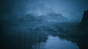Mysterious fog envelops rocky coastline at dusk near tranquil water video