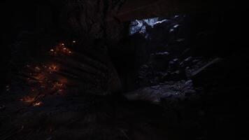 Darkness envelops rocky cave with faint glimmers of light from candles video