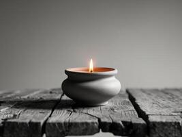 Elegant Clay Pot Candle with Flickering Flame on Rustic Wooden Table Surface photo