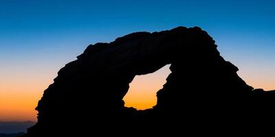 A rock archway with a hole in the middle photo