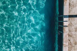 A pool with a blue water and a black ladder photo
