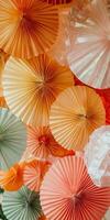 A bunch of paper fans are hanging from the ceiling, with some orange photo