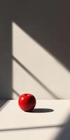 A red apple is sitting on a table in front of a window photo