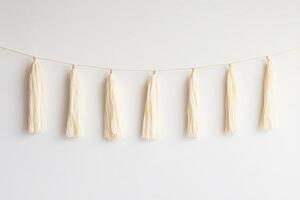 Elegant Cream Tassel Garland Hanging Against Minimalist White Background photo