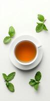 A white cup with a green tea leaf in it sits on a white plate photo
