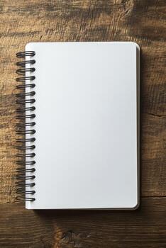 A spiral bound notebook with a blank page sits on a wooden table photo