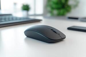 A black computer mouse is sitting on a white desk photo